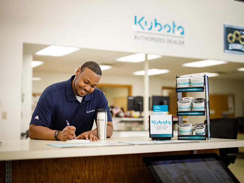 Kubota engine dealership employee writing a parts order at the front counter.