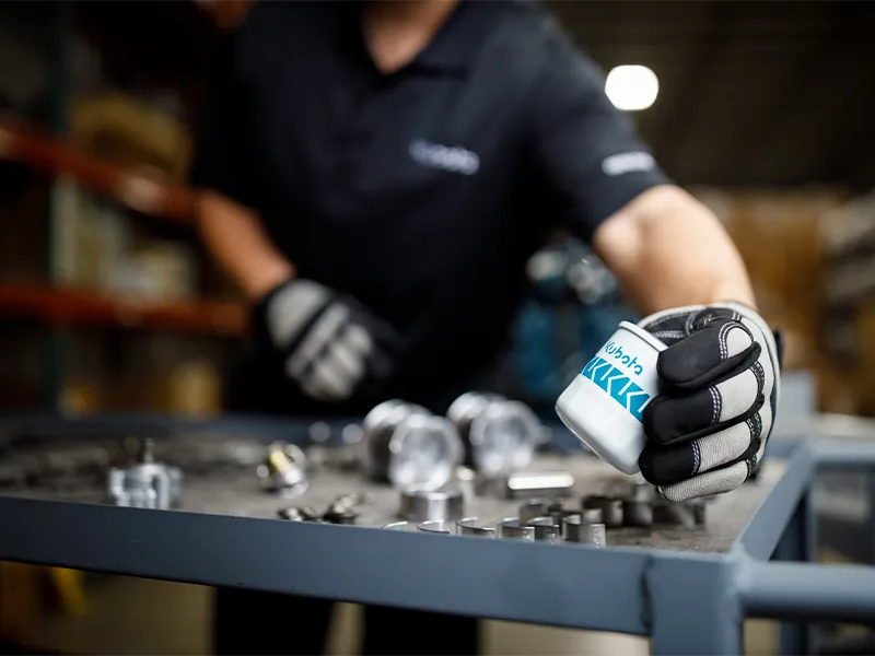 Kubota dealer holding a Kubota engines filter, with a caddy of additional parts in the background.